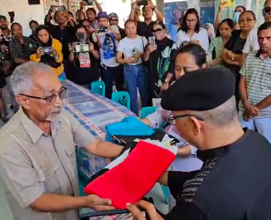 Mantan Perdana Menteri Timor Leste Mari Alkatiri (kiri) menyerahkan bendera Republik Demokratik Timor Leste dan bendera Fretilin ke Nug Katjasungkana, lalu mereka menutup peti dengan kedua bendera tersebut. (Foto Ist)